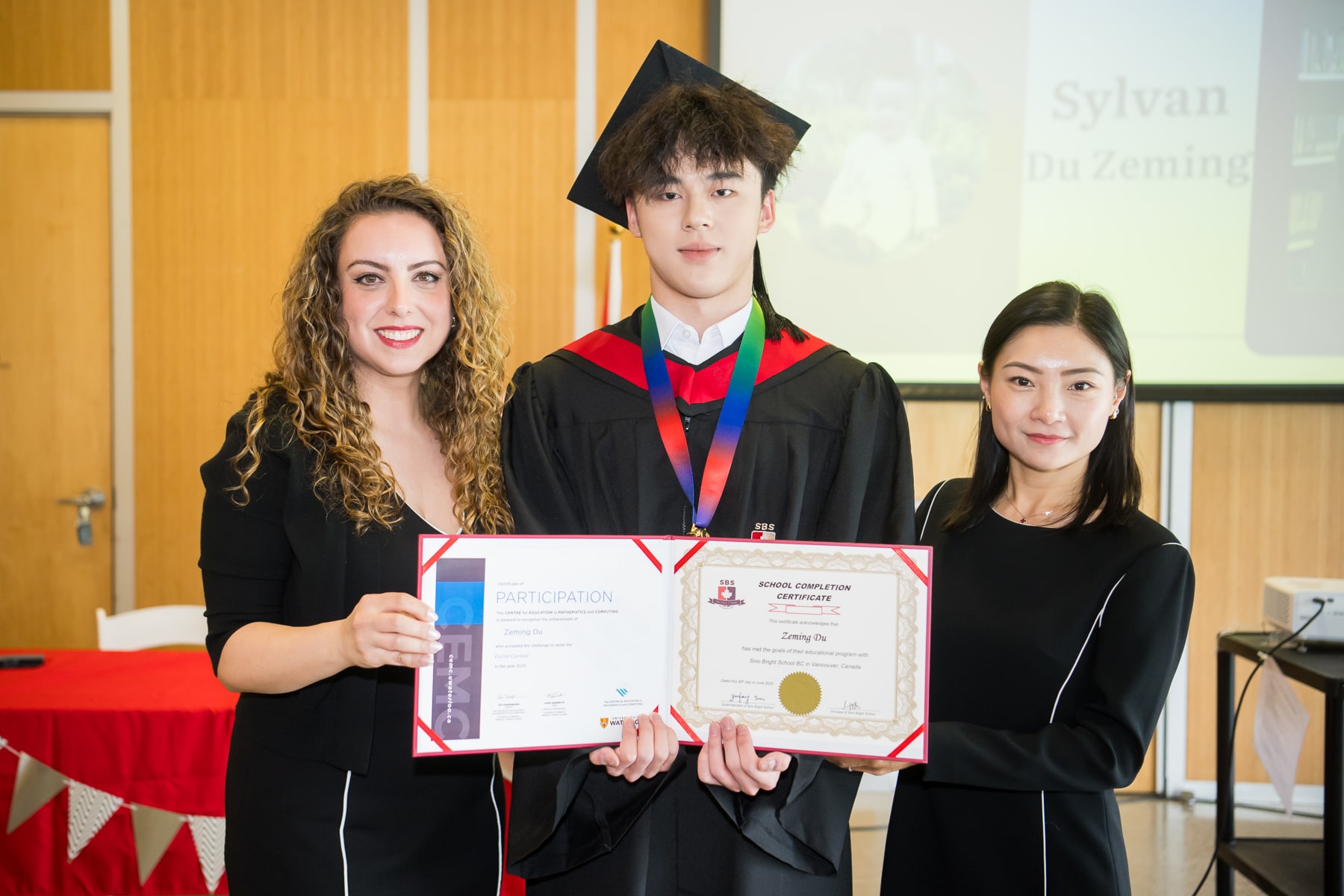 A graduate and teachers presenting the graduation certificate
